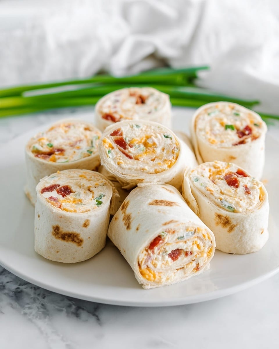 The image shows eight small wrap roll slices placed close together on a white plate sitting on a white marbled surface. Each wrap has two main layers; the outer thin white tortilla wrap with some light brown spots and the inner filling which is creamy white mixed with small bits of orange cheese, little green herbs, and tiny pieces of reddish bacon. The rolls are cut so the spiral layers of the filling are clearly visible, showing a mix of soft texture and colorful bits within. In the background, a blurry white cloth and some green onions add a fresh touch. photo taken with an iphone --ar 4:5 --v 7