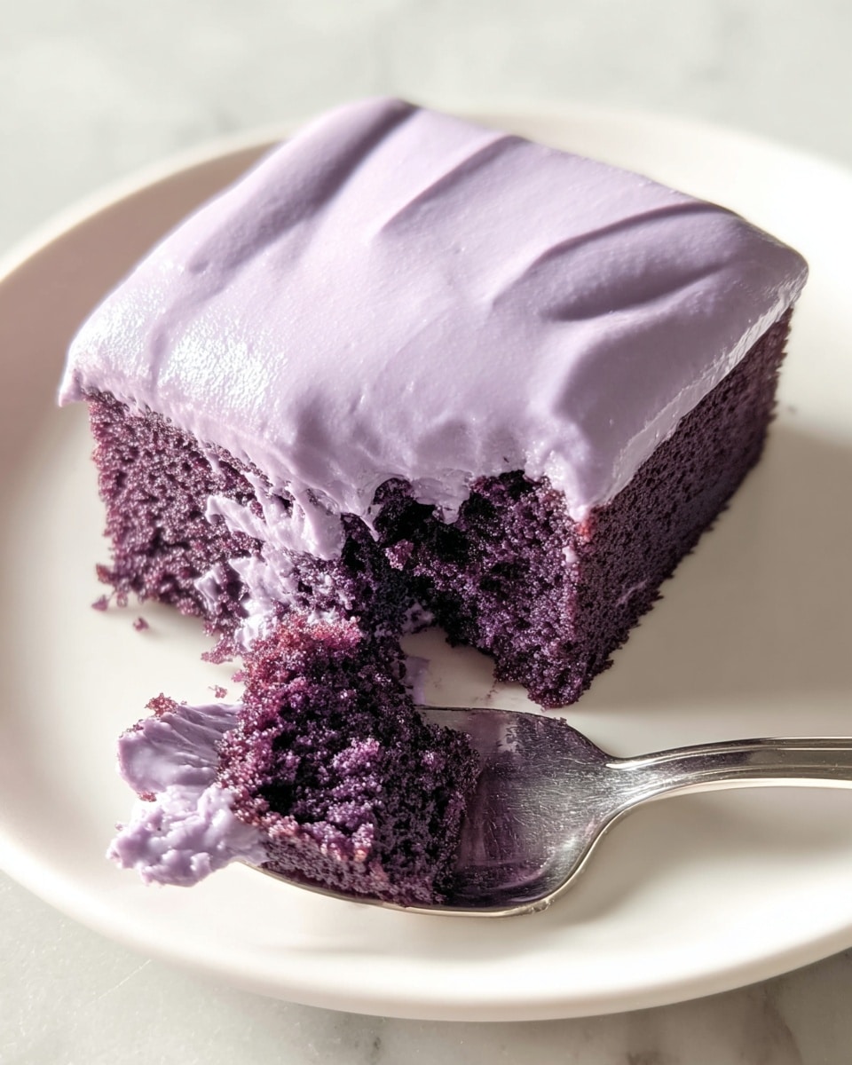 A square-shaped piece of cake with two clear layers is shown. The bottom layer is a dark purple, moist sponge cake with a light texture and small holes. The top layer is a thick, smooth, and creamy light purple frosting that covers the entire cake evenly, slightly dripping down the sides. The cake rests on a white plate, placed on a white marbled surface. The photo is well-lit, showing the cake’s soft and moist texture clearly. photo taken with an iphone --ar 4:5 --v 7