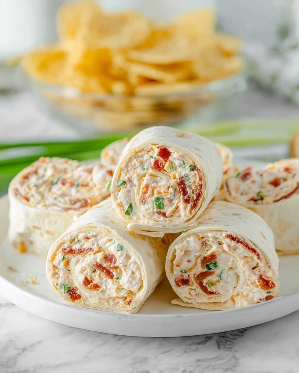 The image shows a white plate stacked with several tortilla pinwheel rolls. Each roll has three visible layers: a soft white tortilla wrap on the outside, a creamy white filling mixed with small orange cheese bits and green herb pieces in the middle, and thin bits of reddish bacon or ham scattered throughout the filling. The pinwheels are cut evenly, displaying the spiral pattern of the layers. The plate sits on a white marbled surface, and the background includes a blurred bowl of light yellow tortilla chips and green onion tops. Photo taken with an iphone --ar 4:5 --v 7