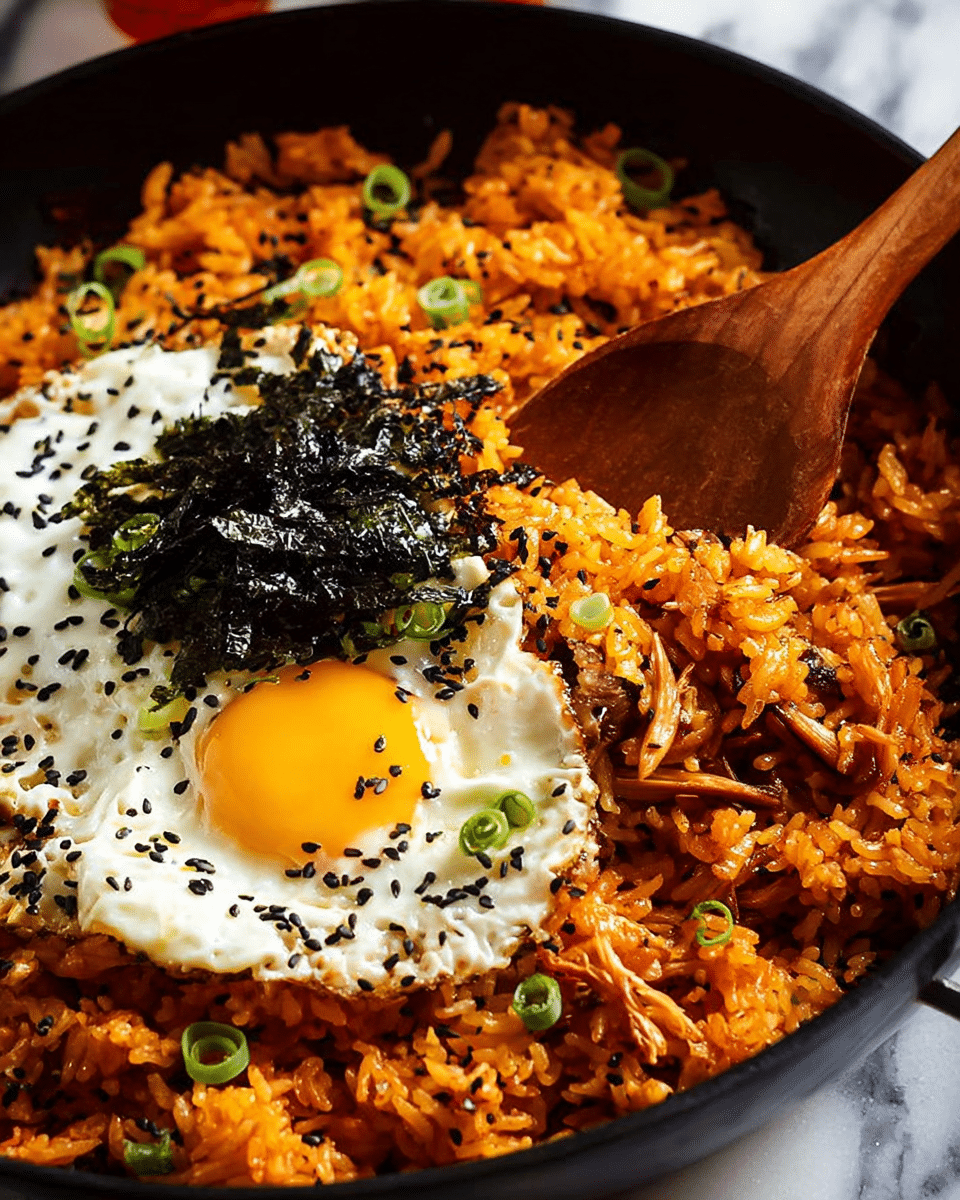 A black pan filled with a dish of orange-colored fried rice mixed with small shredded pieces of meat or mushrooms, topped with thinly sliced green onions and black sesame seeds scattered throughout. On one side, there is a sunny-side-up fried egg with a bright yellow yolk and white edges sprinkled with black sesame seeds. On top of the egg, there are thin strips of dark seaweed. A wooden spoon is partially scooping the rice from the pan. The background is a white marbled texture. Photo taken with an iphone --ar 4:5 --v 7