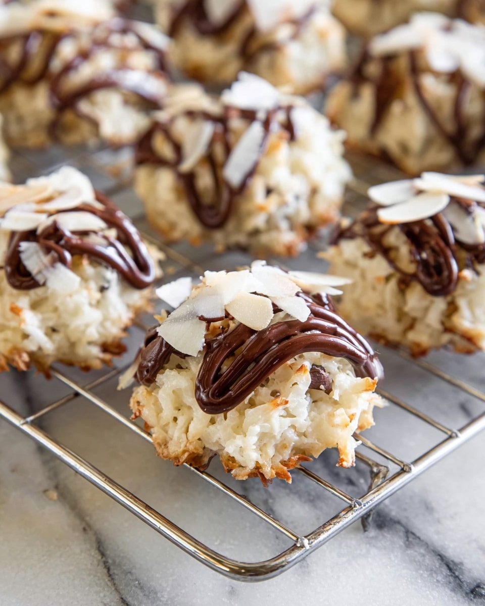 Small round cookie clusters sit on a silver cooling rack over a white marbled surface. Each cluster is made of a base layer of shredded white coconut mixed with bits of chocolate, topped with a swirl of thick dark brown chocolate drizzle, and finished with thin white almond slices scattered on top. The texture of the coconut looks soft with some golden toasted edges visible, while the chocolate drizzle adds a glossy contrast, making the treats look rich and fresh. Photo taken with an iphone --ar 4:5 --v 7