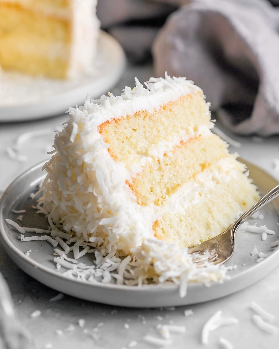 A slice of three-layer cake sits on a white plate with shredded white coconut sprinkled around it. The bottom and top layers are light and fluffy white cake, while the two middle layers are creamy and pale yellow, textured with a coconut filling. The cake is covered in thick white frosting, with more shredded coconut on the outside. A silver fork is gently pressing into the cake from the right side. The cake and plate are set on a white marbled surface. photo taken with an iphone --ar 4:5 --v 7