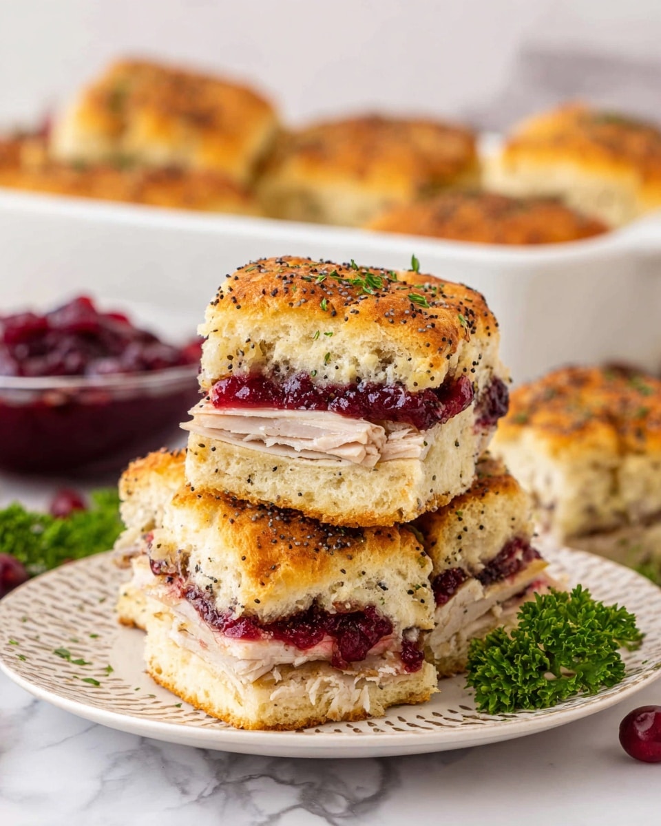 The image shows a small stack of three thick sandwich squares on a white patterned plate, placed on a white marbled surface. Each sandwich has three visible layers: the top and bottom layers are golden, fluffy bread rolls sprinkled with black poppy seeds and small bits of green herbs; the middle section has thin slices of light brown turkey meat, a generous layer of smooth melted white cheese beneath, and a bright, rich red cranberry sauce sitting above the turkey. In the background, slightly blurred, there is a white baking dish filled with more of the same sandwich squares, and on the left side, a clear bowl of dark red cranberry sauce near a few sprigs of fresh green parsley. photo taken with an iphone --ar 4:5 --v 7