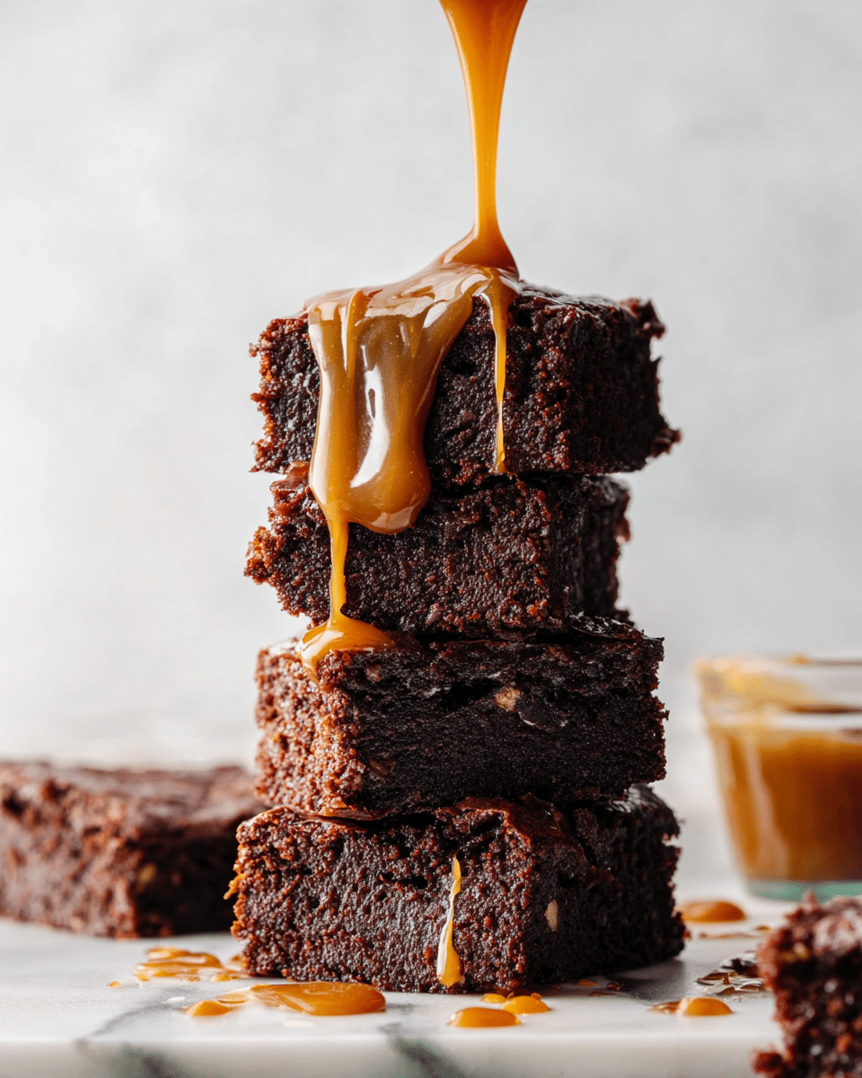 A stack of five thick, dark brown brownies is shown on a white marbled surface. Each brownie has a dense, slightly crumbly texture with small bits visible inside. A thick, smooth caramel sauce is being drizzled onto the top brownie, flowing down the sides of the stack in glossy golden streams. Some caramel drips are also on the surface around the stack. In the background, out of focus, is a small clear glass container partially filled with caramel sauce. Photo taken with an iphone --ar 4:5 --v 7