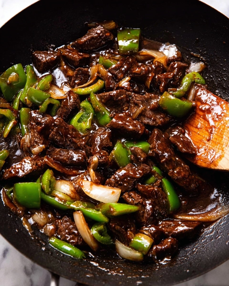 The image shows a close-up of a stir fry in a black wok. The dish has many pieces of dark brown beef mixed with bright green bell pepper chunks and translucent white onion slices. The ingredients are coated in a thick, shiny, dark brown sauce. A wooden spatula is partially visible on the right side, slightly covered with sauce, lifting some of the stir fry. The background shows a white marbled texture. photo taken with an iphone --ar 4:5 --v 7