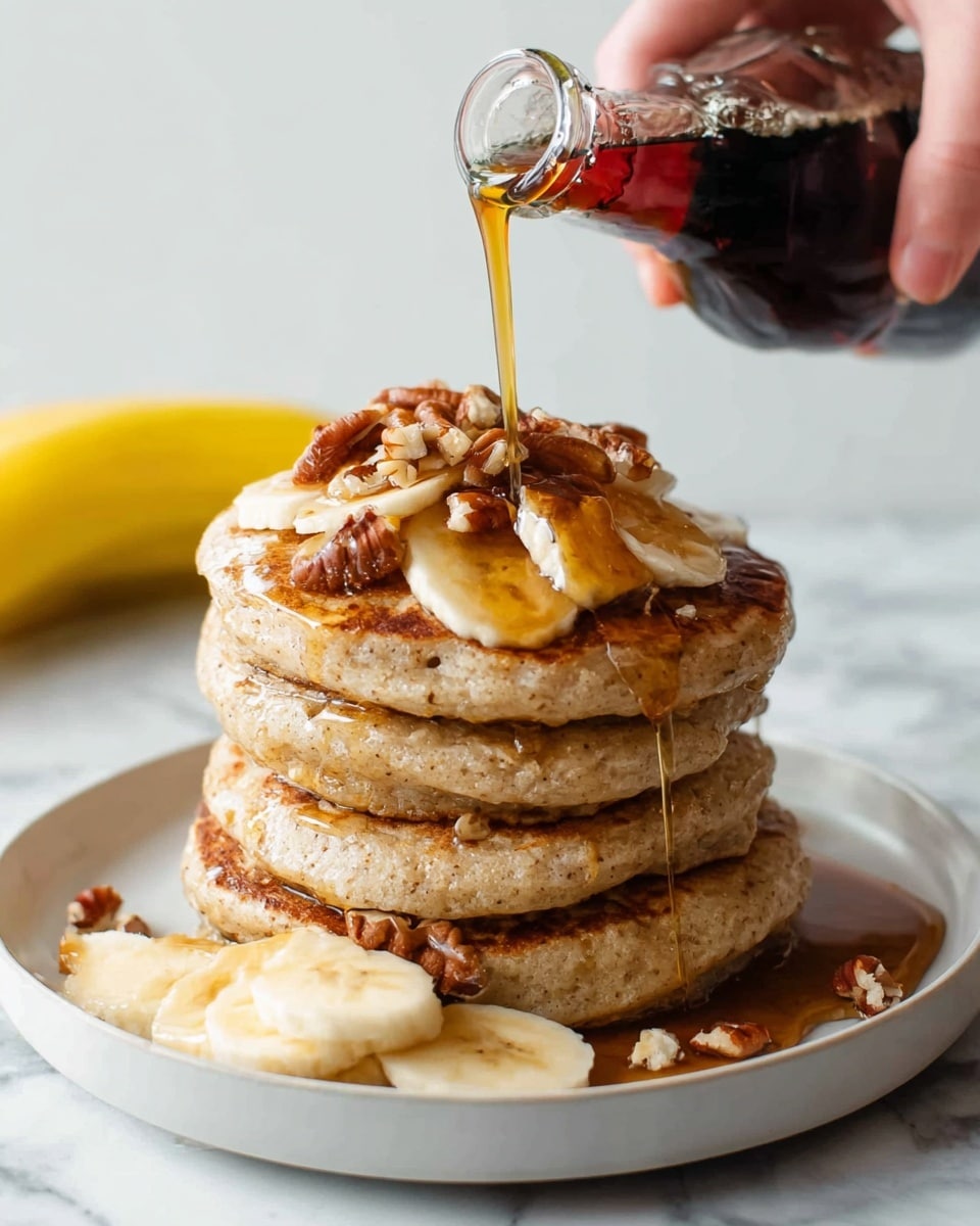 A stack of four thick, fluffy pancakes with a light golden-brown color sits on a white plate, topped with several slices of banana and small pieces of pecans. Rich amber syrup is being poured from a dark bottle by a woman's hand, dripping down the sides of the pancakes and pooling on the plate. Additional banana slices are placed next to the stack on the plate. The background shows a white marbled surface with a ripe yellow banana out of focus behind the plate. photo taken with an iphone --ar 4:5 --v 7