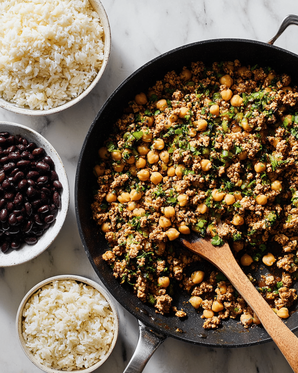 A large black skillet contains a cooked mix of small tan chickpeas, light brown crumbled tofu or ground meat, and small green chopped herbs and vegetables, all spread evenly with a wooden spoon resting inside the skillet. Next to it, there are two white bowls, one filled with plain white rice showing soft, fluffy grains, and the other filled with dark black beans with a shiny texture. The scene is set on a white marbled surface with soft natural light. photo taken with an iphone --ar 4:5 --v 7