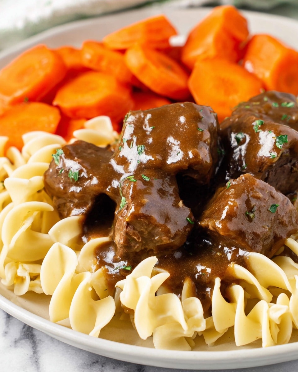 The image shows a close-up of a white plate with three layers of food. The bottom layer is light yellow egg noodles with a soft, curly texture. On top of the noodles are several pieces of dark brown beef chunks covered in a thick glossy brown gravy with small green herb sprinkles. At the back of the plate, there are several slices of bright orange cooked carrots, slightly glossy and smoothly cut. The food is all placed on a white marbled surface. photo taken with an iphone --ar 4:5 --v 7