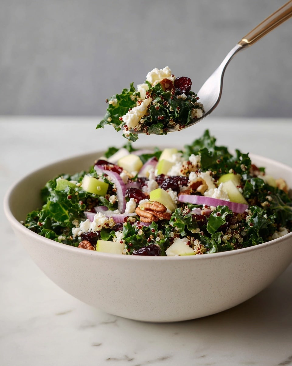 The image shows a white bowl filled with a fresh salad. The base layer is dark green kale leaves with a rough texture. On top, there are small white crumbles of cheese, light green cubes of apple, and thin slices of purple-red onion. Scattered through the salad are small round grains of quinoa in white and red colors, along with glossy dark red dried cranberries and brown pecan pieces. A silver fork is holding a small mixed bite of all these ingredients above the bowl. The bowl is placed on a white marbled surface. photo taken with an iphone --ar 4:5 --v 7