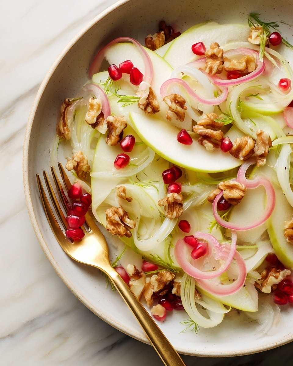 The image shows a close-up of a salad in a white bowl set on a white marbled surface, with thinly sliced green apple layers forming the base, light pink thin onion slices scattered throughout, and round pale white fennel slices with green tips interspersed. Small pieces of light brown toasted walnuts are spread on top, along with a few bright red pomegranate seeds adding contrast. A gold fork rests on the salad, holding a piece of apple, onion, and fennel. The textures range from smooth fruit slices to crunchy nuts, creating a fresh and colorful mix. photo taken with an iphone --ar 4:5 --v 7